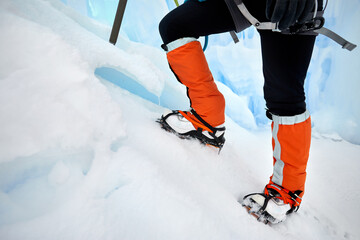 Woman climber in ice crampons near frozen waterfall