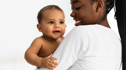 African American mom holding her cute infant at home