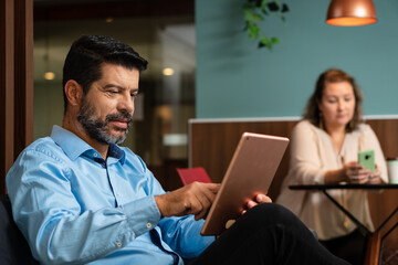 mature business man checking report on digital tablet on sofa in office lobby. .