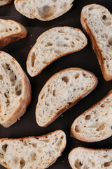 Italian ciabatta bread slices on dark stone concrete background, top view
