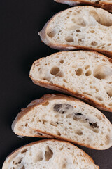 Sliced ciabatta bread on black background. Italian white bread. Top view.