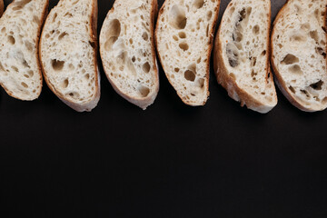 Sliced ciabatta bread on black background. Italian white bread. Top view with copy space.
