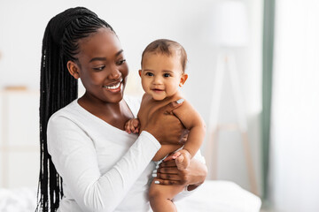 African American mom hugging her cute infant and posing