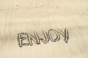 Enjoy genießen handschriftlich in den Sand geschrieben am Strand