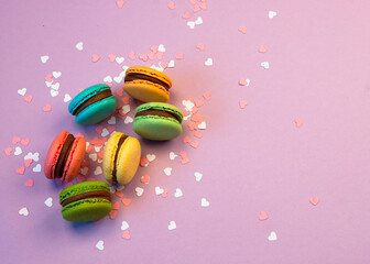 Multicolored macarons with pink and white hearts on a pink background.
