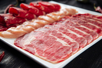 Sliced raw beef meat on the plate on the wooden background
