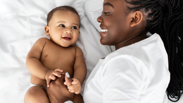 African American mom lying in bed with her cute baby