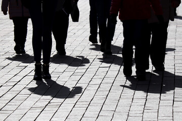 Silhouettes and shadows of people walking on the city street. Concept of society or population