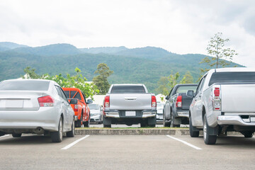 Fototapeta na wymiar Car parked in asphalt parking lot and empty space for car park in nature with trees and mountain background .Outdoor parking lot