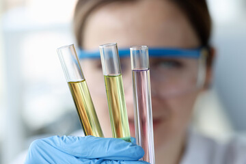 Woman scientist holding test tubes with multicolored liquids in her hands closeup