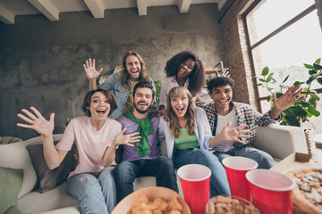 Portrait of attractive funky cheerful friends sitting on sofa having fun free time day good mood in house brick loft style indoors