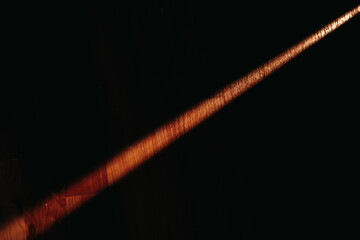 Fototapeta premium A beam of light on a black background falls on a wooden floor