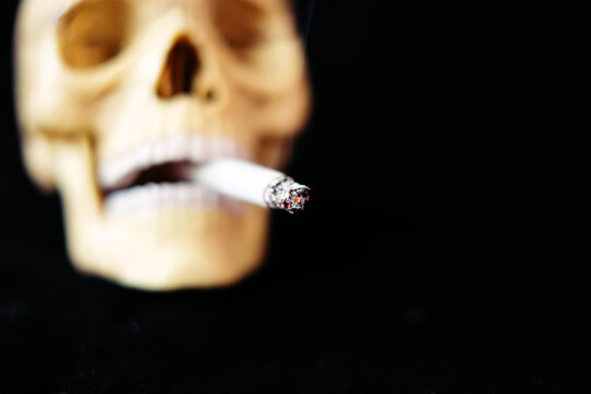 Skull and burning cigarette. Death from smoking concept. Defocused