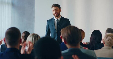 Young successful entrepreneur concludes his speech at business conference to applause of audience. Concept of mentoring and coaching in biz.