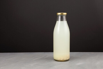 Rejuvelac - healthy fermented drink. Clear glass bottle on dark background with copy space....