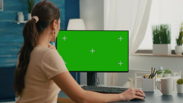Business woman searching marketing information on internet using personal computer with mock up green screen chroma key. Female working with isolated pc at project company in living room