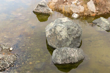 Muddy yellow waters of a dry river at the bottom of a mountain canyon between stones on a sunny day