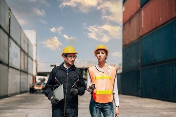 workers teamwork man and woman in safety jumpsuit workwear with yellow helmet use laptop and talking at cargo container shipping warehouse. transportation import,export logistic industrial service