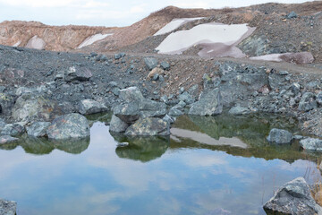 Muddy yellow waters of a dry river at the bottom of a mountain canyon between stones on a sunny day