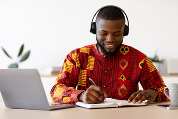 Positive African American Man In Ethnic Shirt And Headset Study With Laptop