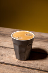 Fototapeta na wymiar Kaffee auf Holzpallte mit braun gelben Hintergrund