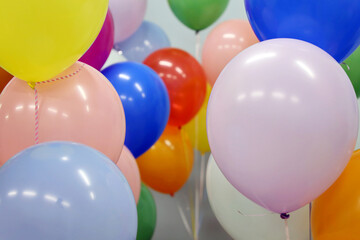 Helium balloons with ribbons in the office. Colorful festive background for birthday celebration, corporate party