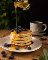 pancakes with blueberries and honey on a dark background