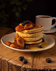 pancakes with bananas fried in caramel on a dark background