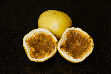 Passion fruit cut to make a juice with a black granite background.