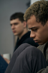 Staged photo illustrates problems and conflicts in gay couple relationships. Moment of showdown: two young men are sitting on the floor near each other. Partners are upset and wistful.