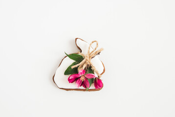 Flat lay of Easter gingerbreads bunny shape, green leaves and pink flowers. Minimalist Easter. White background. Happy Easter card.