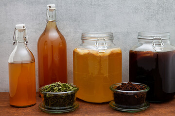 Glass jars with kombucha fermented on ground coffee beans and lemon verbena leaves tea beverage. Alternative medicine.