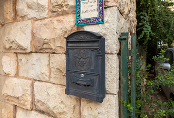 Evening  view of old metal mailbox with coat of arms of Jerusalem, hangs on wall of apartment building on a Yehuda Alkalai Street in the old district of Jerusalem Talbia - Komiyut in Jerusalem, Israel