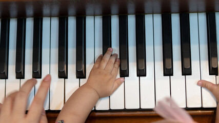 Close up of Baby and Adult Playing with Piano Keys Together