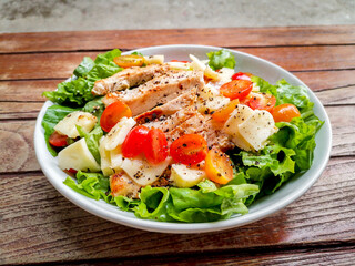 Healthy food concept. Grilled chicken breast salad with fresh red tomato, green lettuce, and...