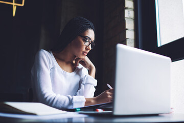 Serious woman working with documents and laptop