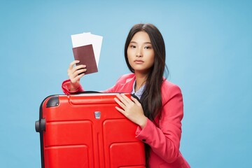 A woman of Asian appearance with a suitcase shows a passport and tickets 