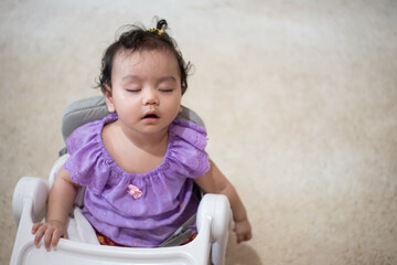 Cute little asian baby girl Sitting asleep on the dining table After eating full in the house