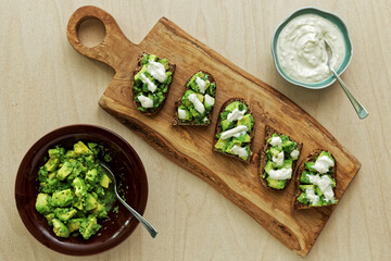Preparing sandwiches with guacamole avocado spread and tahini and yoghurt dressing.