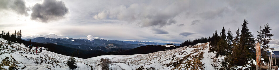 Fototapeta na wymiar Panorama on the sunny winter day in the Carpathian mountains. Breathtaking view of snow-capped peaks, tourists and Mount Hoverla. Scenic conceptual landscape.