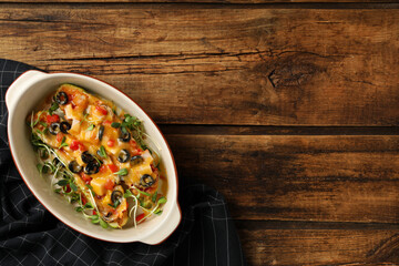 Baking dish with delicious stuffed zucchinis served on wooden table, top view. Space for text