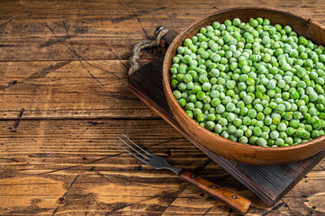 Cold Frozen green peas in a wooden plate. Wooden background. Top view. Copy space