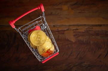 Bitcoin token in a trolley on wooden table.