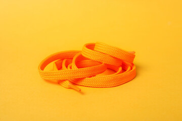 Orange shoe lace on yellow background. Stylish accessory