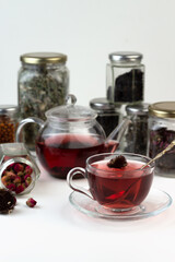 Homemade herbal tea. A remedy that boosts immunity and relieves stress. Glass teapot and tea with a healthy drink. Transparent jars with dried herbs and berries.