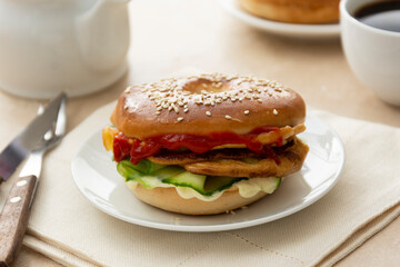 Bagel sandwich with cucumber, sauce, egg, cheese. Breakfast or lunch, closeup bagel bun served with coffee