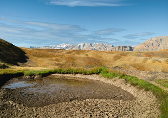 Dried up waterhole surrounded by Himalayas in summer. Komic, India.