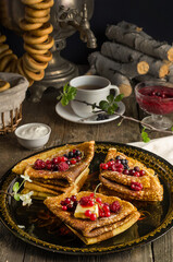 Still life with traditional Ukrainian and Russian pancakes for the Maslenitsa holiday with butter and berries on a black tray