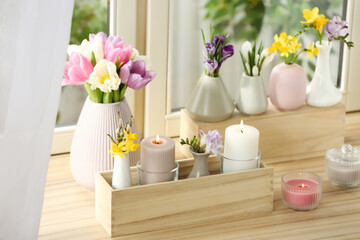 Beautiful spring flowers with burning candles on window sill
