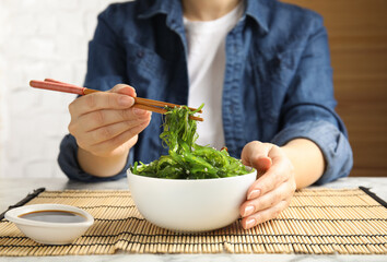 Woman eating Japanese seaweed salad at table, closeup